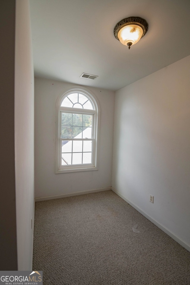 spare room featuring carpet floors, visible vents, and baseboards