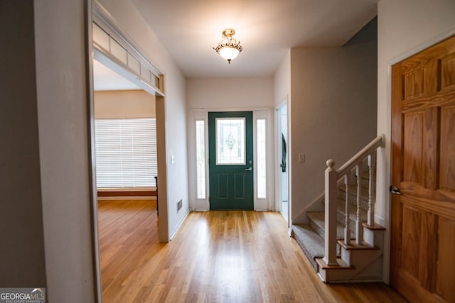 foyer with light wood finished floors, stairway, and baseboards