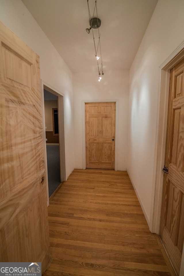 corridor featuring rail lighting and wood finished floors