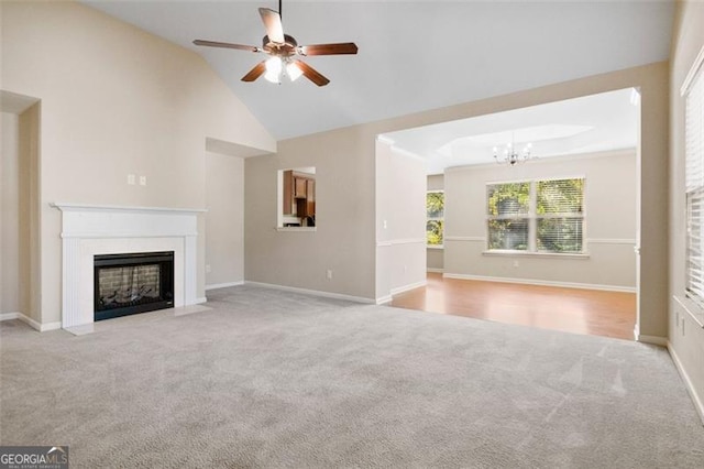 unfurnished living room with light colored carpet, high vaulted ceiling, and ceiling fan with notable chandelier