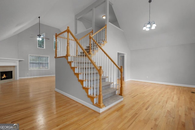 interior space with light hardwood / wood-style floors, high vaulted ceiling, and ceiling fan with notable chandelier