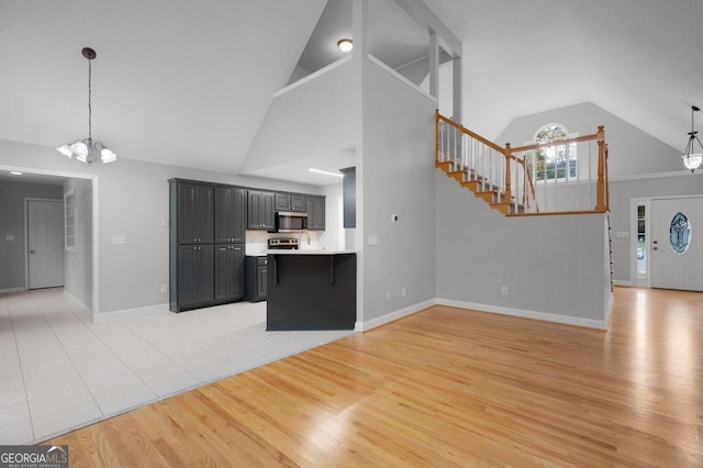 kitchen with hanging light fixtures, a notable chandelier, high vaulted ceiling, and light wood-type flooring