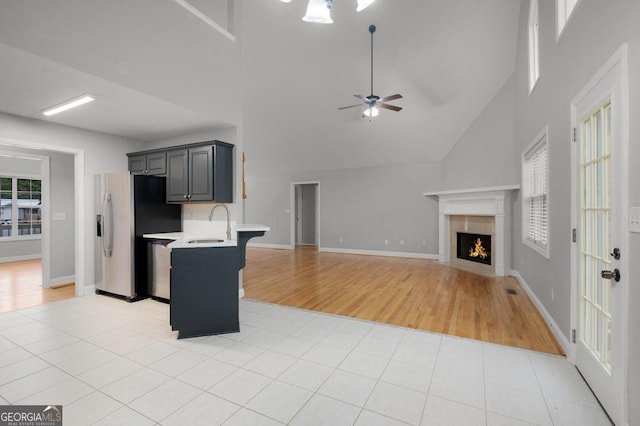 kitchen with sink, a kitchen bar, light wood-type flooring, high vaulted ceiling, and ceiling fan