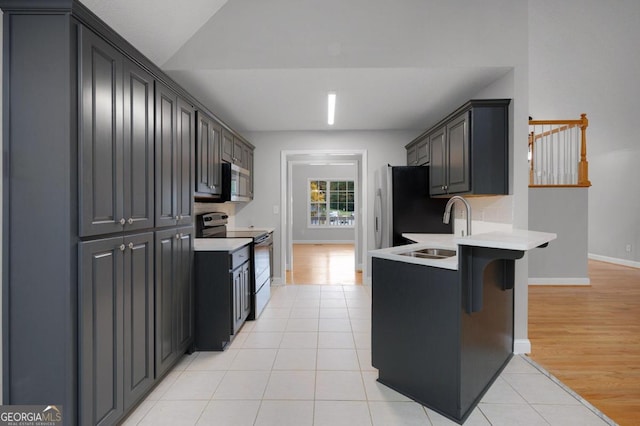 kitchen with light hardwood / wood-style flooring, kitchen peninsula, stainless steel appliances, sink, and a kitchen bar