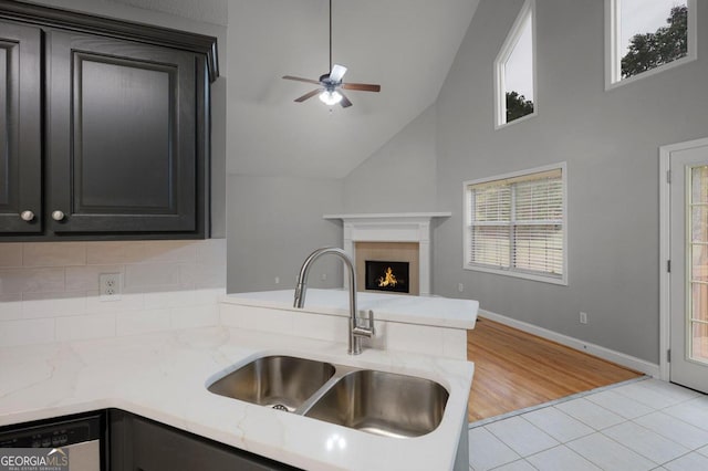 kitchen with light tile patterned flooring, dishwasher, sink, ceiling fan, and high vaulted ceiling