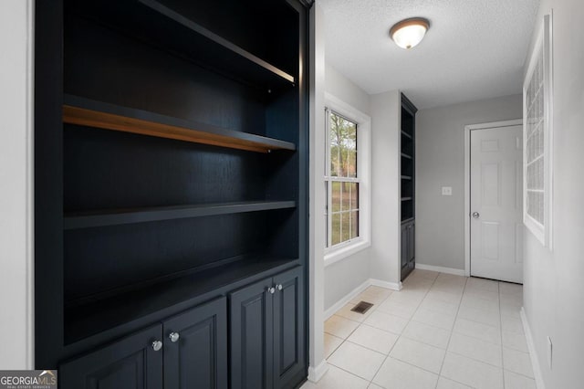 hall featuring a textured ceiling and light tile patterned flooring