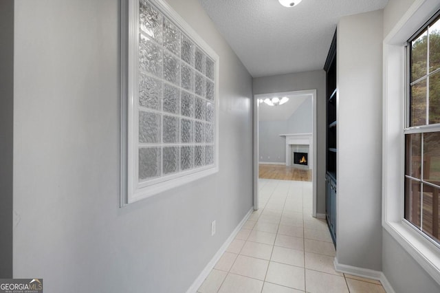 hall with a textured ceiling and light tile patterned floors