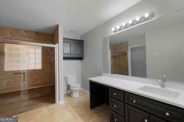 bathroom with a textured ceiling, a shower with shower door, toilet, tile patterned floors, and vanity