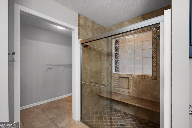 bathroom with tile patterned floors, a textured ceiling, and an enclosed shower