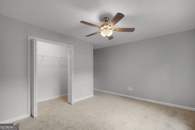 unfurnished bedroom featuring light carpet, a textured ceiling, a closet, and ceiling fan