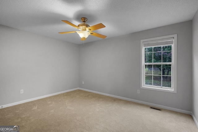 carpeted spare room with a textured ceiling and ceiling fan