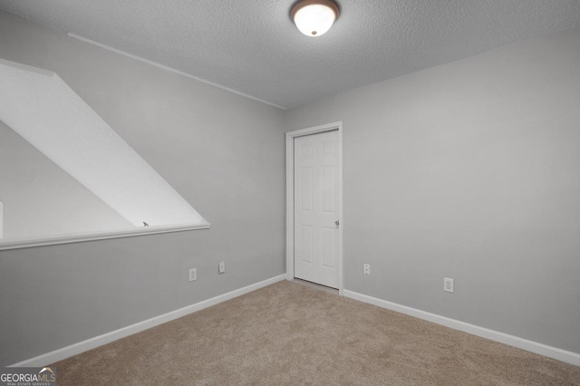 carpeted empty room featuring a textured ceiling