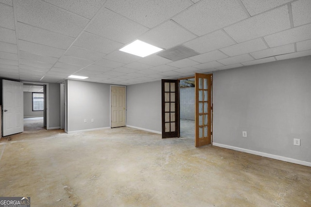 basement featuring french doors and a drop ceiling