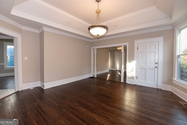 empty room featuring ornamental molding, a tray ceiling, and dark hardwood / wood-style flooring