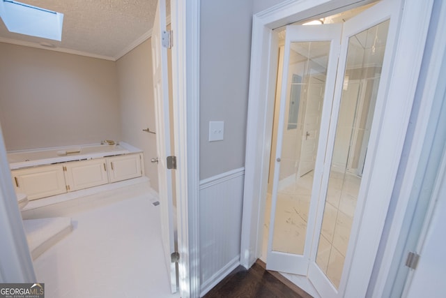 bathroom with crown molding, a textured ceiling, a skylight, and hardwood / wood-style floors