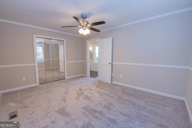 unfurnished bedroom featuring a textured ceiling, a closet, ceiling fan, crown molding, and carpet