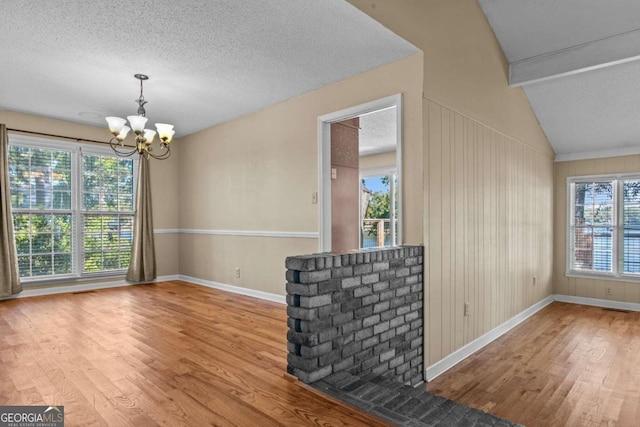 unfurnished dining area with baseboards, wood finished floors, a chandelier, and a wealth of natural light