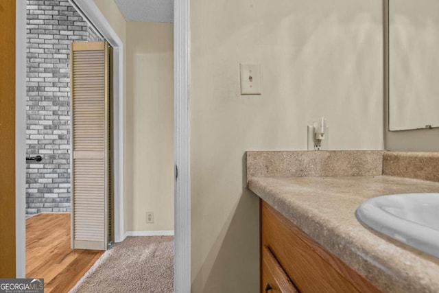 bathroom featuring vanity and brick wall