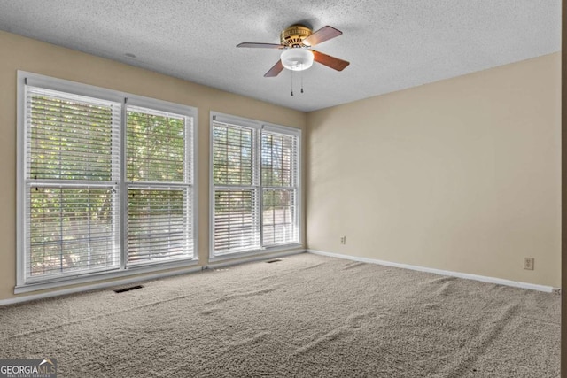 empty room with visible vents, carpet flooring, baseboards, a textured ceiling, and a ceiling fan