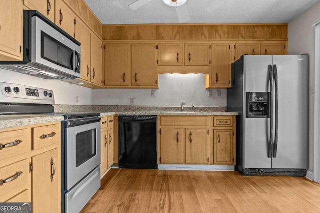 kitchen with ceiling fan, appliances with stainless steel finishes, light countertops, a sink, and light wood finished floors