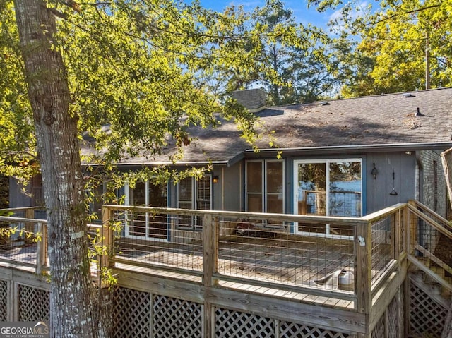 rear view of house featuring a shingled roof and a deck
