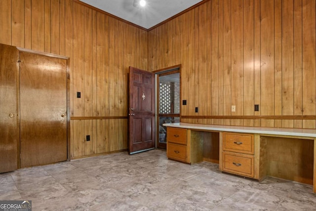 unfurnished office featuring wood walls and built in study area