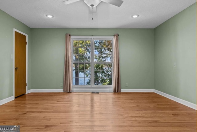 unfurnished room featuring light wood finished floors, a textured ceiling, a ceiling fan, baseboards, and visible vents