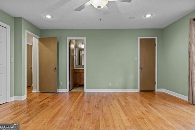 unfurnished bedroom featuring a textured ceiling, recessed lighting, baseboards, ensuite bathroom, and light wood-type flooring