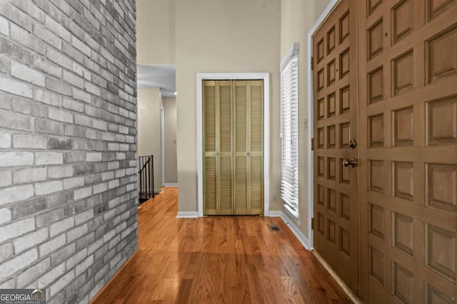 entrance foyer with visible vents, a high ceiling, light wood finished floors, and baseboards