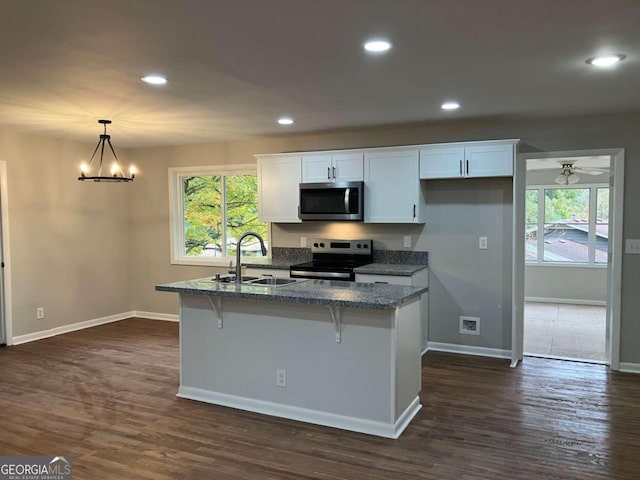 kitchen featuring stainless steel appliances, sink, decorative light fixtures, and white cabinets