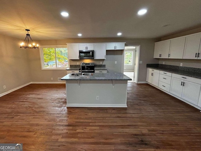 kitchen featuring appliances with stainless steel finishes, sink, dark wood-type flooring, and pendant lighting