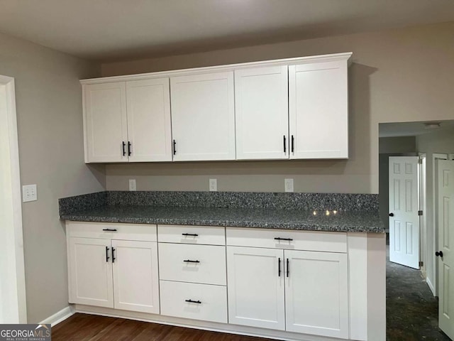 kitchen with white cabinetry, dark stone countertops, and dark hardwood / wood-style flooring