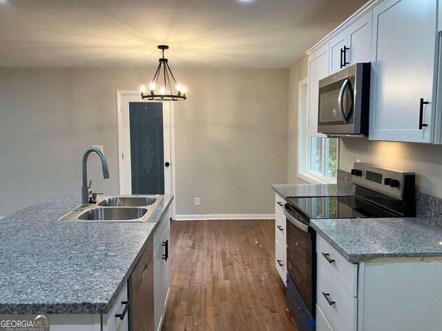 kitchen featuring white cabinetry, dark hardwood / wood-style floors, sink, pendant lighting, and stainless steel appliances