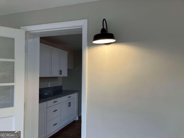 kitchen featuring white cabinetry, dark wood-type flooring, dark stone counters, and pendant lighting