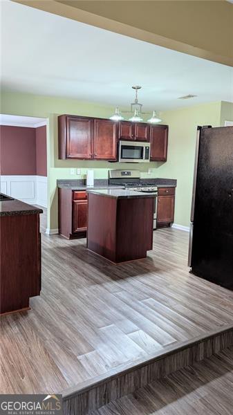 kitchen featuring stainless steel appliances, light hardwood / wood-style flooring, and a center island