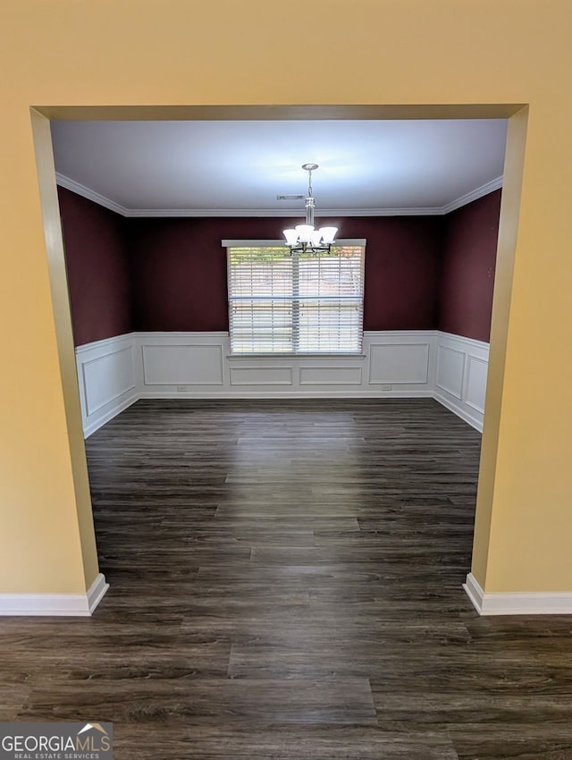 unfurnished dining area featuring dark wood-type flooring, a chandelier, and ornamental molding