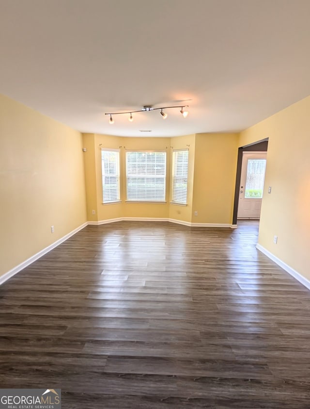 empty room featuring dark wood-type flooring and rail lighting