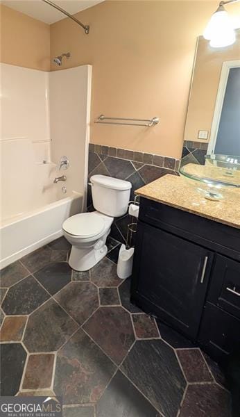 full bathroom with shower / tub combination, vanity, toilet, and tile walls