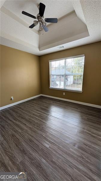 spare room featuring ceiling fan, a textured ceiling, dark hardwood / wood-style floors, and a raised ceiling