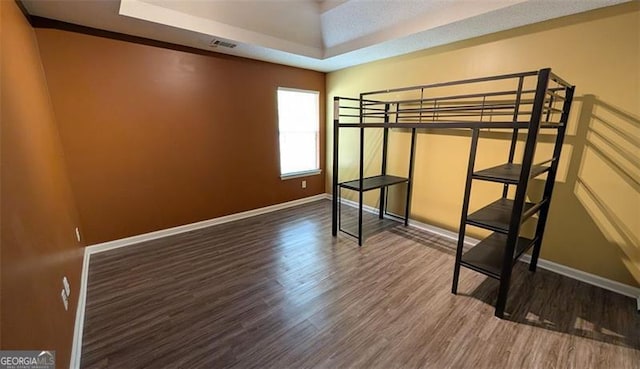 unfurnished bedroom with a tray ceiling and hardwood / wood-style flooring