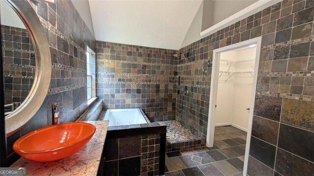 bathroom with tile walls, sink, plus walk in shower, and lofted ceiling