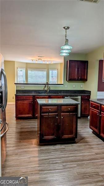 kitchen with stainless steel appliances, hanging light fixtures, sink, and light wood-type flooring