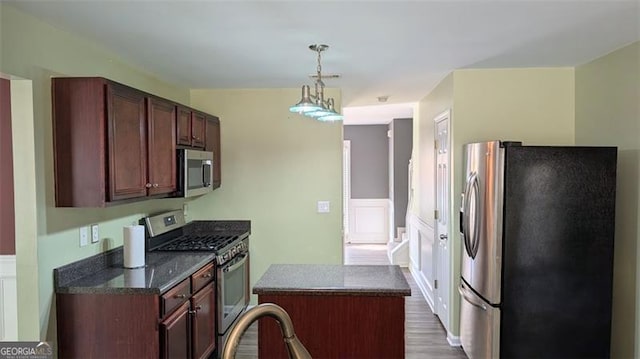 kitchen featuring pendant lighting, appliances with stainless steel finishes, wood-type flooring, and a kitchen island