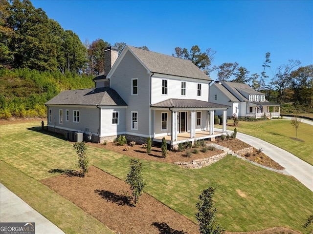 farmhouse featuring covered porch, central AC, a chimney, and a front yard