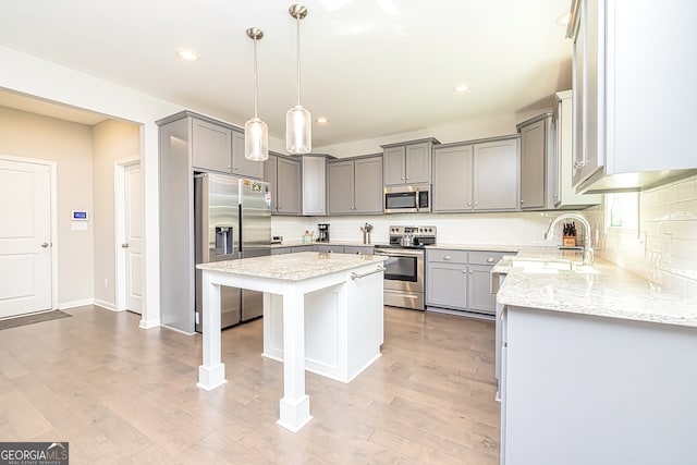 kitchen featuring a kitchen island, appliances with stainless steel finishes, light hardwood / wood-style flooring, and pendant lighting