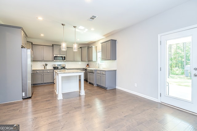 kitchen featuring appliances with stainless steel finishes, hardwood / wood-style flooring, pendant lighting, and a kitchen island