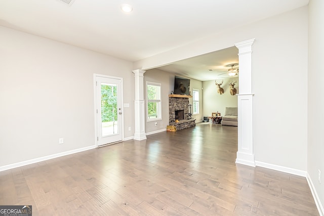 unfurnished living room with decorative columns, a fireplace, hardwood / wood-style flooring, and ceiling fan