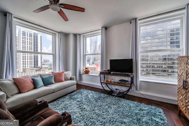 living room with ceiling fan, dark wood-type flooring, and a wealth of natural light