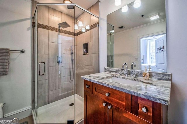 bathroom with vanity, a shower with shower door, and ornamental molding