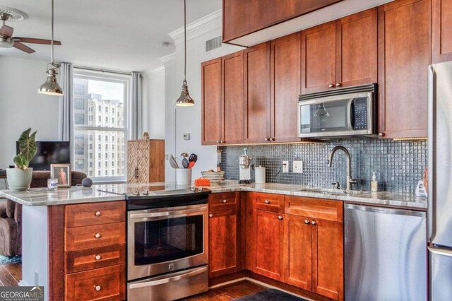 kitchen with kitchen peninsula, hanging light fixtures, stainless steel appliances, light stone counters, and dark hardwood / wood-style floors